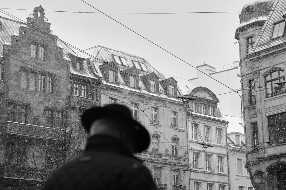 Ein Schwarz-weiss Foto einiger Häuser in der Gerbergasse in Basel`s Altstadt. Im Vordergrund sieht man unscharf einen Mann mit Hut vorbeigehen. (Bastian Peter, Street photography, Basel, Schweiz)